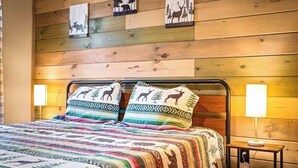 A bed with patterned bedding, a metal headboard, and wall-mounted animal-themed decor. - Private Retreat w/ Hot Tub, Pool Table, & Scenic Views (Sevierville)