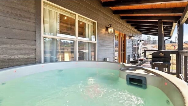 A hot tub with a wooden deck and a covered patio area. - Private Retreat w/ Hot Tub, Pool Table, & Scenic Views (Sevierville)