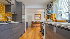 Una cocina moderna con armarios grises, lavadora y comedor con mesa y sillas.