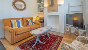 Una sala de estar con sofá, mesa de centro, televisor y objetos decorativos.