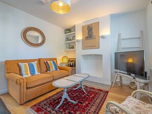 A living room with a sofa, coffee table, TV, and decorative items. - Seagrass Cottage - Perfect holiday cottage with parking in Whitstable. Sleeps 6 (Kent)
