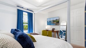 A bedroom with a bed, a desk with a laptop, a painting, and a mirror on the wall. - Wells Retreat: 3BR, Firepit, Pickleball, Sleeps 9 (Wells)