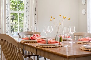 Une table à manger dressée avec des assiettes, des verres et un vase rempli de fleurs jaunes.