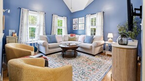 A living room with a blue wall, two sofas, a coffee table, and a TV. - Wells Retreat: 3BR, Firepit, Pickleball, Sleeps 9 (Wells)