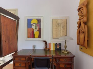 A wooden desk with a chair, books, a lamp, and two framed artworks on the wall. - La Sorgente by Interhome (Saturnia)