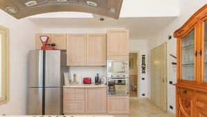 A modern kitchen with a gas stove, stainless steel appliances, wooden cabinets, and a wooden cabinet with glass doors. - La Sorgente by Interhome (Saturnia)