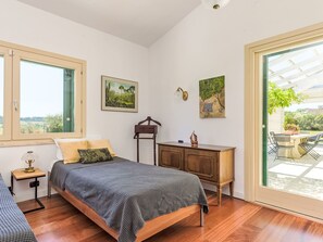 Une chambre à coucher comprenant un lit, une table de chevet, une lampe et une porte-fenêtre donnant sur un espace extérieur.