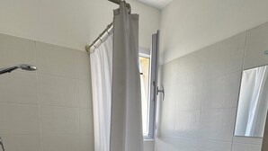 Een badkamer met douche, toilet, wastafel en spiegel.