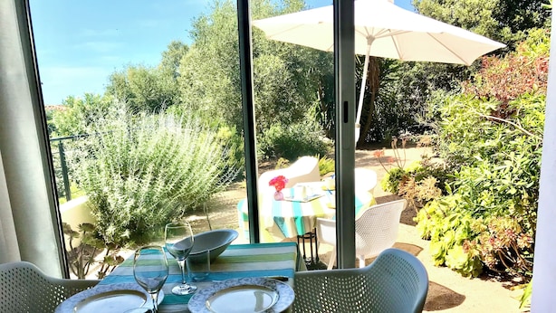 Een eethoek met een tafel voor twee personen, een groot raam en uitzicht op buiten.