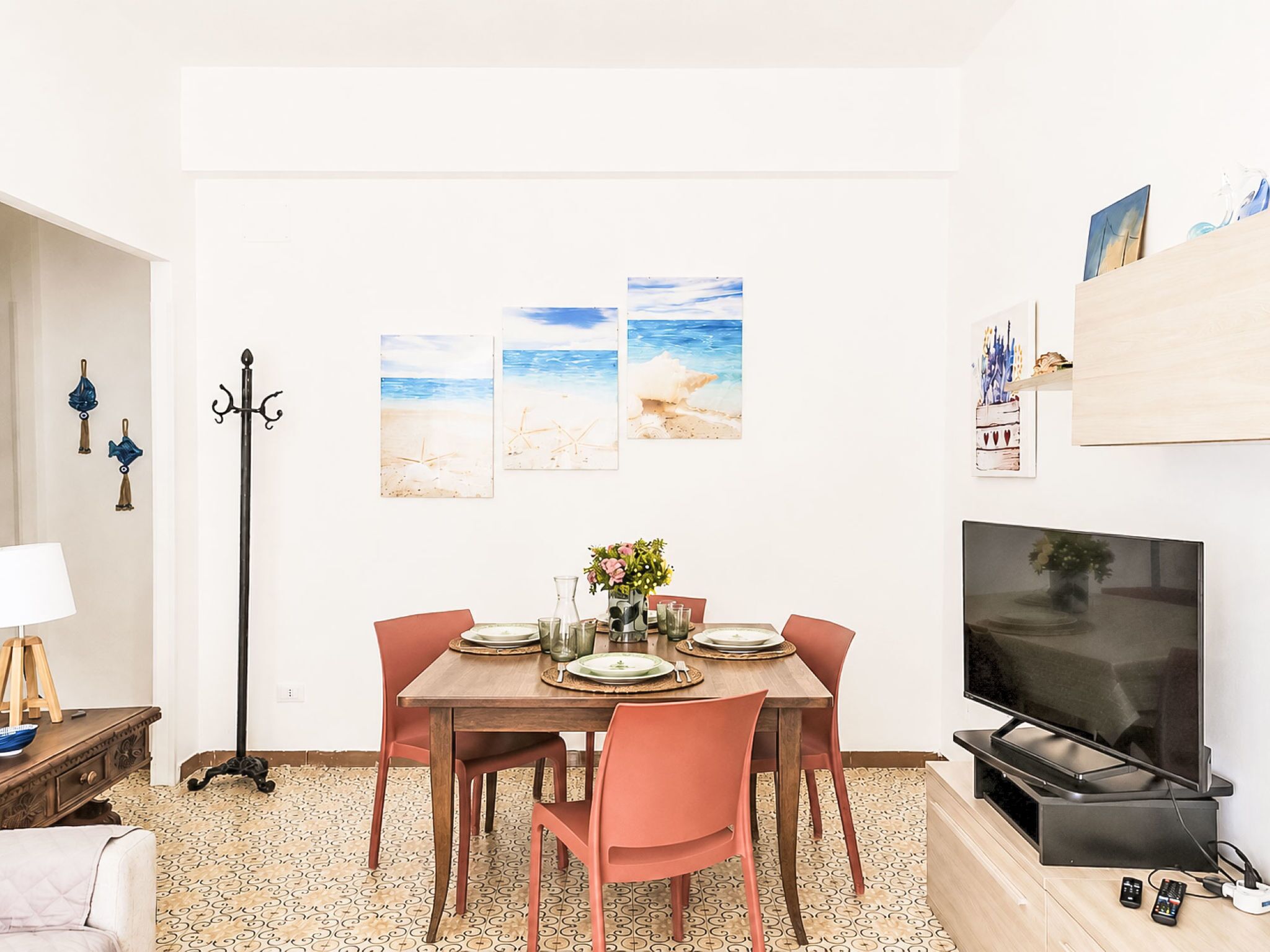 A dining area with a table set for four, a television, and artwork on the wall.