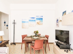 A dining area with a table set for four, a television, and artwork on the wall. - Bemi' al mare by Interhome (Terracina)