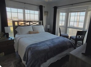 Ein Hotelzimmer mit Bett, Sessel, Schreibtisch und großen Fenstern.