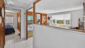 A room with a wooden ceiling, a window with blinds, a star decoration, and a table with items.