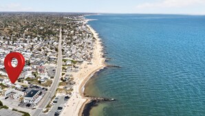 An aerial view of a coastal town with a beach, roads, and buildings.