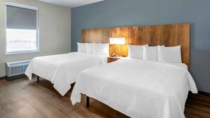 A hotel room with two beds, a wooden headboard, a bedside lamp, and a window with a view. - 3 Stylish Units Near Lakes Regional Park - 2.6 mi | Free Breakfast | Pool Access (Fort Myers)