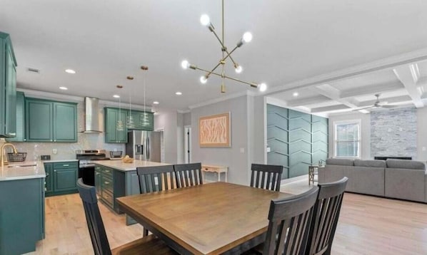 A modern kitchen with teal cabinets, a wooden dining table, and a central island. - Spacious 4 br 3 ba! Minutes to Benz stadium, airport, downtown, and AU Center. (Atlanta)