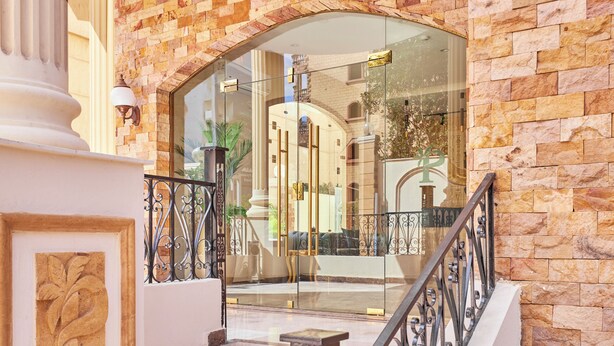 A grand entrance with a stone facade, a glass door, and a metal railing.