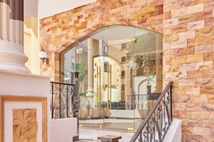 A grand entrance with a stone facade, a glass door, and a metal railing.