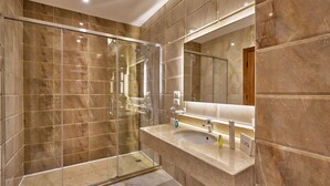 A modern bathroom with a glass-enclosed shower, a sink with a mirror, and marble tiles.