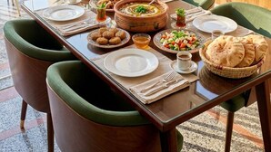 A dining table set with plates, bowls, and a bowl of soup, surrounded by chairs.