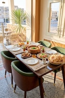 A dining table set with plates, bowls, and a bowl of soup, surrounded by chairs.