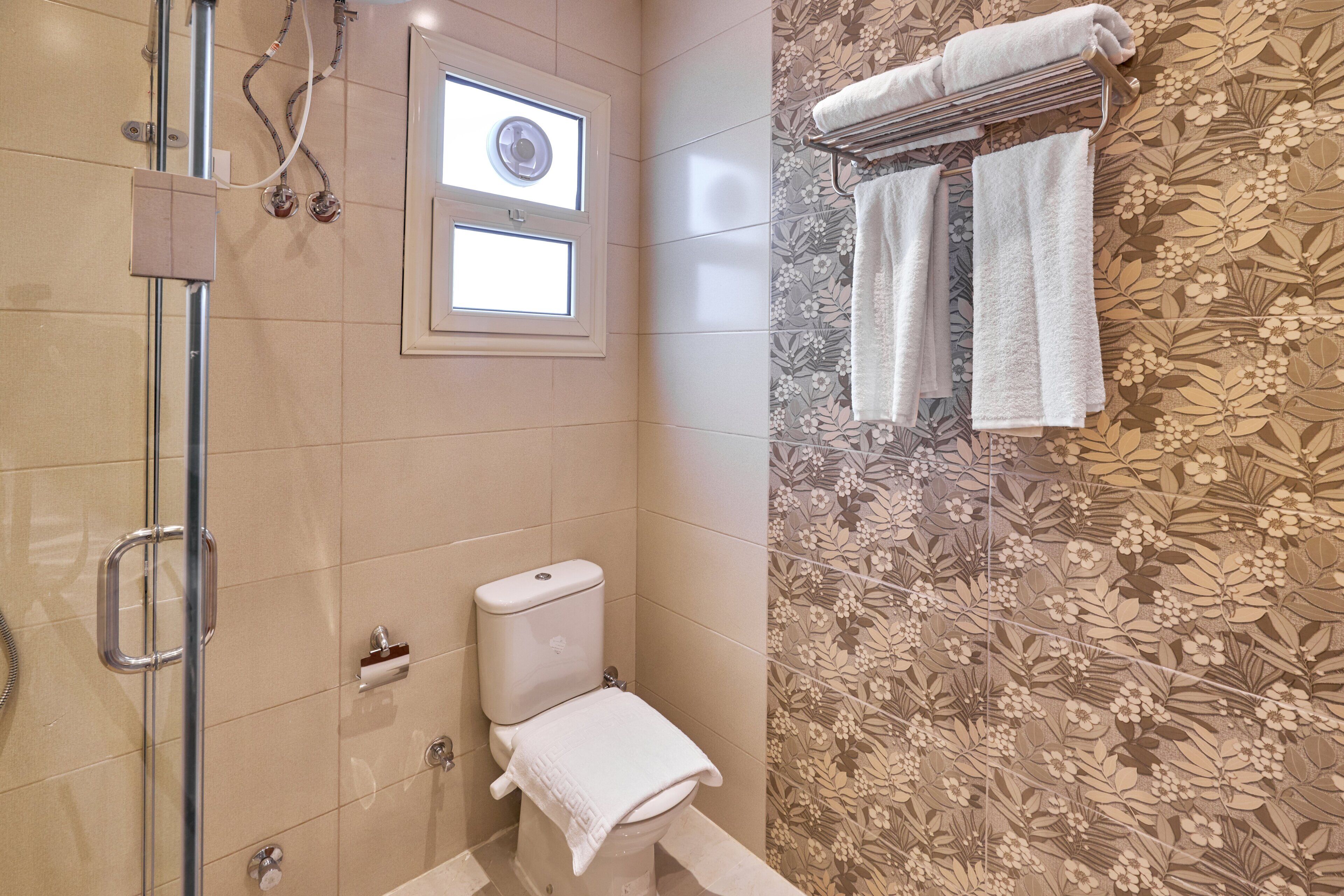 Une salle de bain avec des toilettes, une douche et une fenêtre.