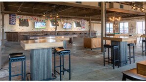A spacious bar area with high ceilings, exposed beams, and a rustic aesthetic. - The Hostel KC  (Kansas City)