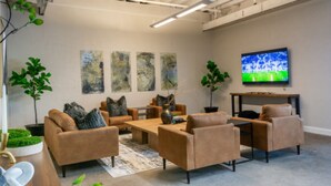 A modern living room with sofas, a coffee table, a TV, and artwork on the wall. - The Hostel KC  (Kansas City)