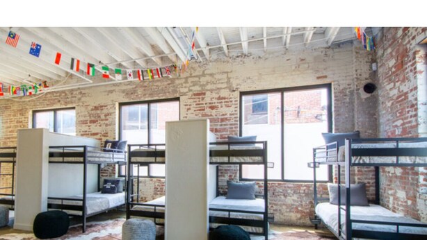 A hostel room with bunk beds, a brick wall, and a cowhide rug. - The Hostel KC  (Kansas City)