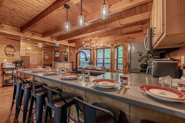 A wooden cabin interior with a central island, bar stools, and a kitchen area. - Dreamy Secluded Cabin Near Dollywood and GSMNP (Sevierville)