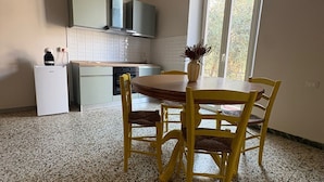 A kitchen with a dining area, a white refrigerator, a window with a view, and a tiled floor. - Residence Corso Roma in the heart of Montecatini Terme (Montecatini Terme)