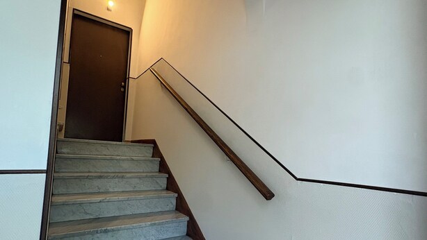 A staircase with marble steps, a wooden handrail, and a door at the top. - Residence Corso Roma in the heart of Montecatini Terme (Montecatini Terme)