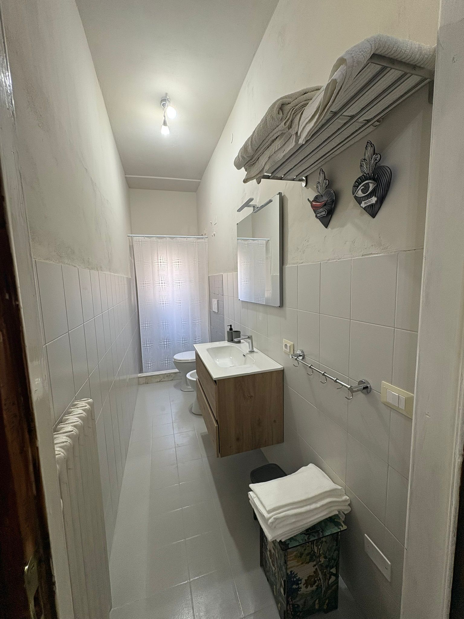 Un baño estrecho con tocador de madera, un espejo y un perchero para toallas.