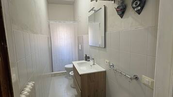 Un baño estrecho con tocador de madera, un espejo y un perchero para toallas.
