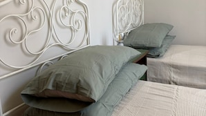 A twin room with a metal headboard, two beds with green pillows, and a bedside table. - Residence Corso Roma in the heart of Montecatini Terme (Montecatini Terme)