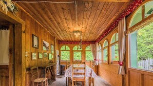 A wooden cabin with a dining area, large windows, and a fireplace.