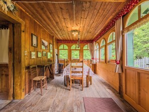 A wooden cabin with a dining area, large windows, and a fireplace.