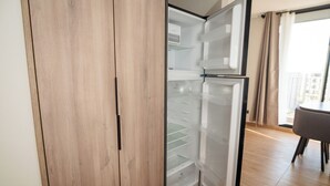 Moderni keittiö, jossa on sisäänrakennettu jääkaappi, puukaapit sekä ruokailutila pöytineen ja tuoleineen.