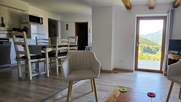 Una sala de estar moderna con comedor, cocina y un ventanal con vistas al exterior.