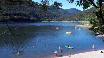 Un lago con barcos y gente, rodeado de colinas cubiertas de bosque.