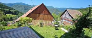 A rural setting with two wooden barns, a grassy yard, and a mountainous backdrop. - Between Alsace and the Vosges - Les Hauts de Kruth (Kruth)