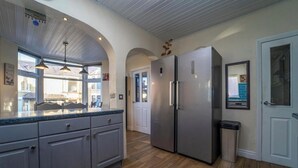 Cucina con un frigorifero spazioso, una finestra vista e una porta che dà su un'altra stanza.