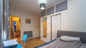Una camera da letto con un letto, una scrivania, una sedia, un termosifone e una porta con uno specchio.