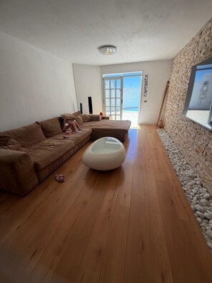 Ein modernes Wohnzimmer mit einem Ecksofa, einem Glastisch und einer Steinwand.