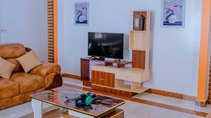 A living room with a sofa, a television, a coffee table, and two wall-mounted paintings.