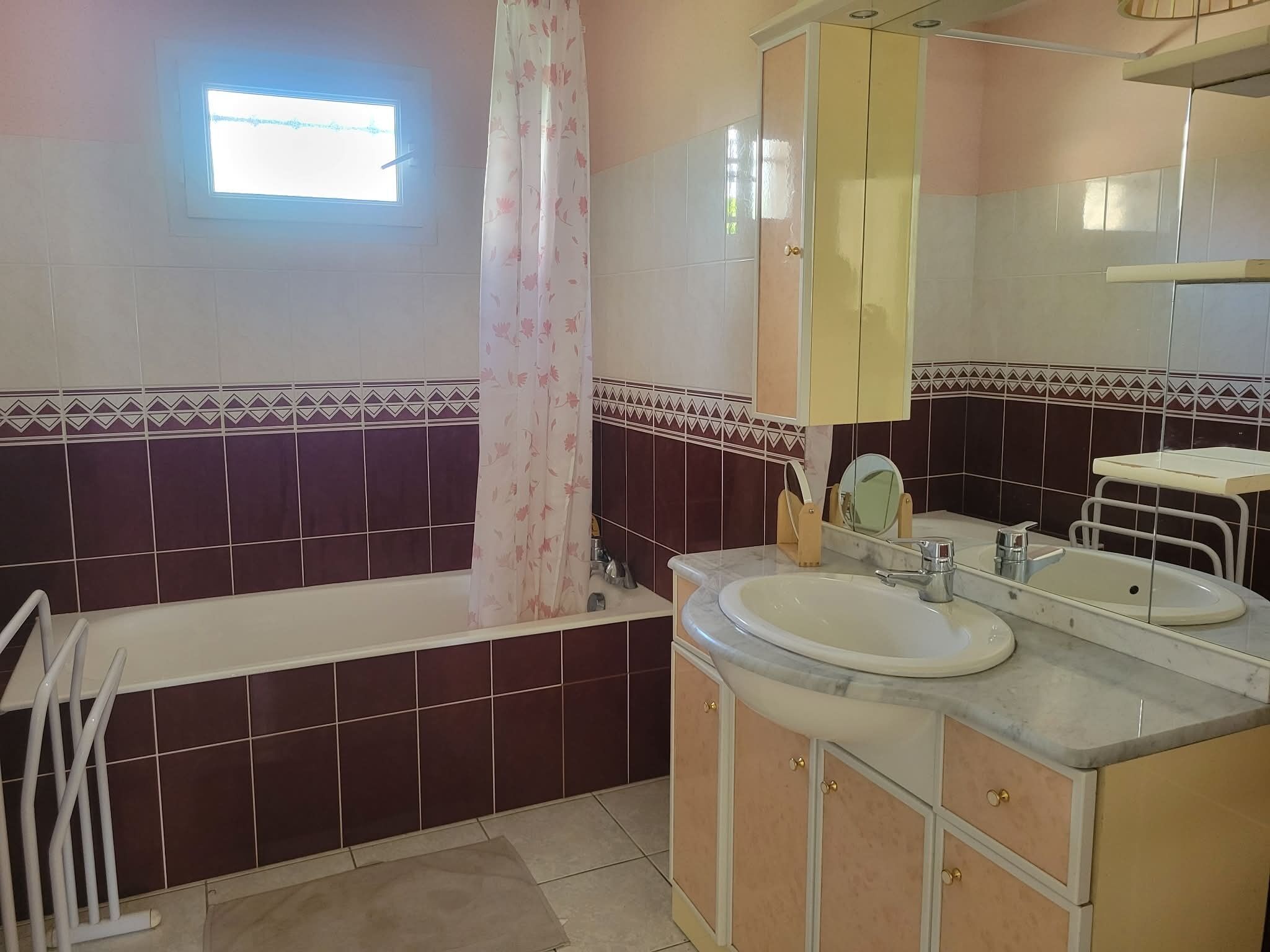 A bathroom with a bathtub, two sinks, a mirror, and a window.