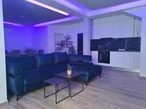 A modern living room with a sectional sofa, a coffee table, and a kitchen area with white cabinets and a black countertop. - ★★★★ Villa Bella Vita - Big Private Pool - Tranquility ★★★★ (Duge Njive)