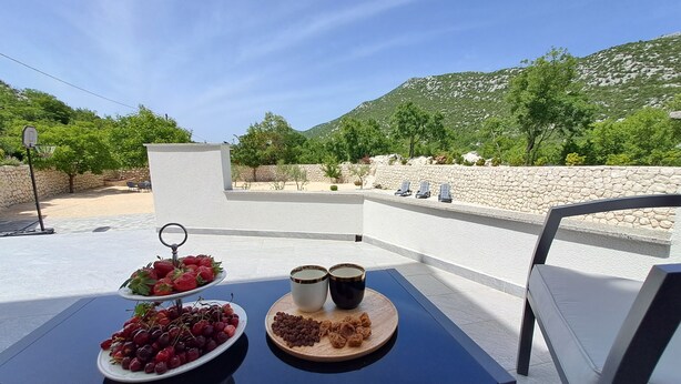 Ein Tisch mit Obst und Nüssen, ein Basketballkorb und eine Steinmauer mit Stühlen.