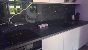 Eine moderne Küche mit schwarzer Marmorarbeitsplatte, einem eingebauten Backofen und weißen Schränken.