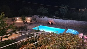 Ein Schwimmbecken mit Steinwänden, umgeben von Vegetation und einem Berg im Hintergrund.